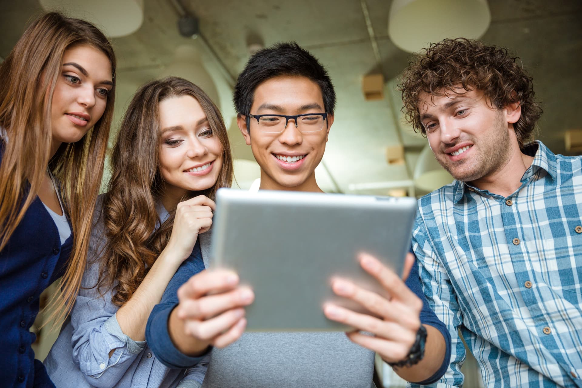 A group gathered around a tablet, smiling as they look at it together.