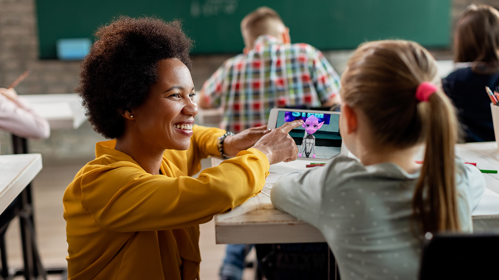 Two students looking at a tablet together in a classroom.
