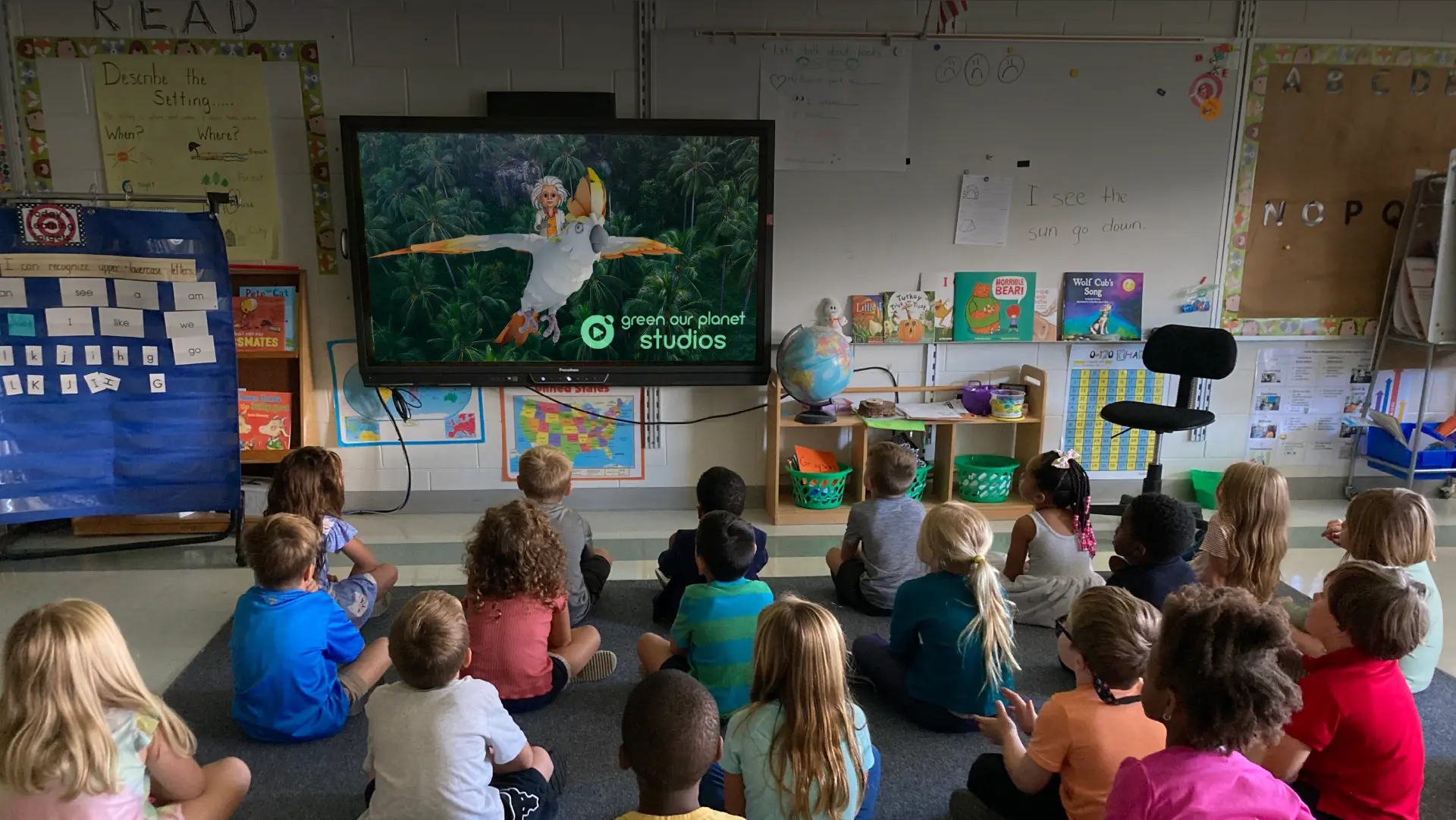 Students watching a Green Our Planet Studios character come to life in the classroom