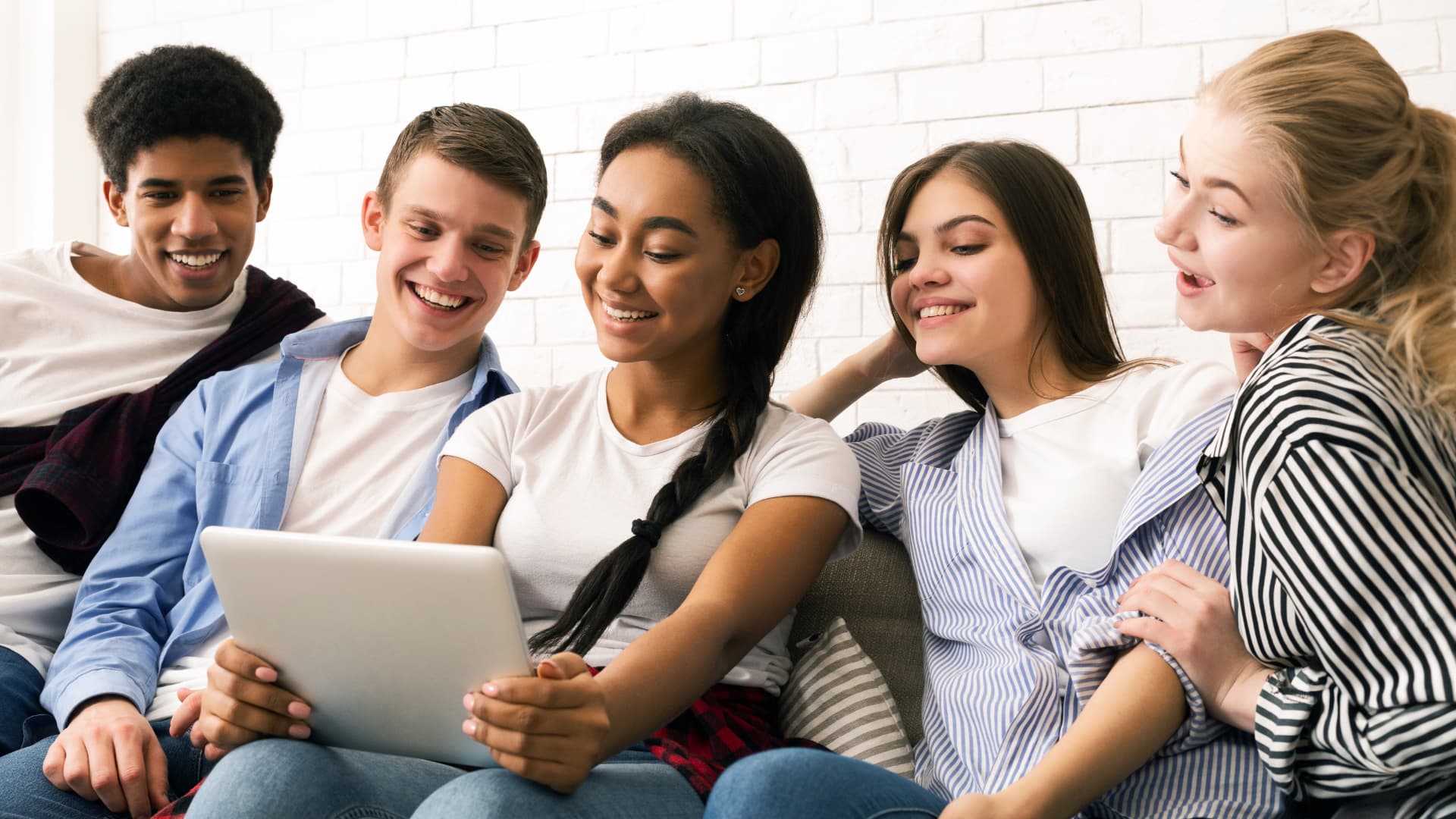 Students gathered together watching a tablet during a classroom session.