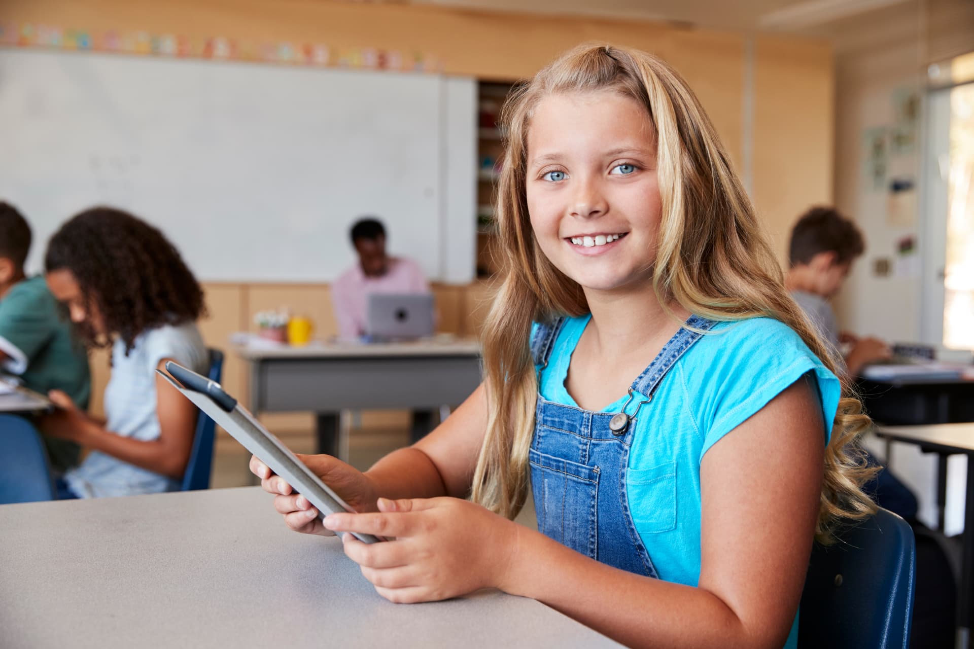 A student smiling while using a tablet in class